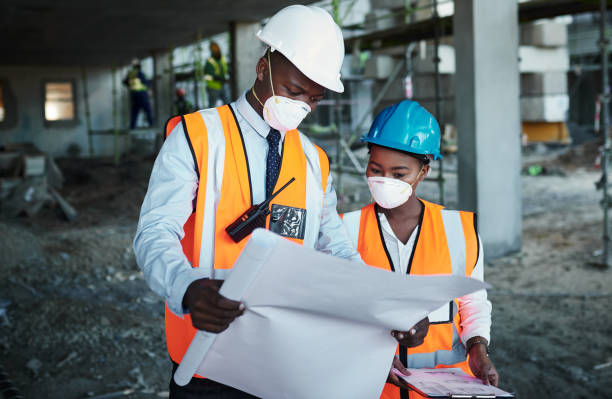Shot of a young man and woman going over building plans at a construction site