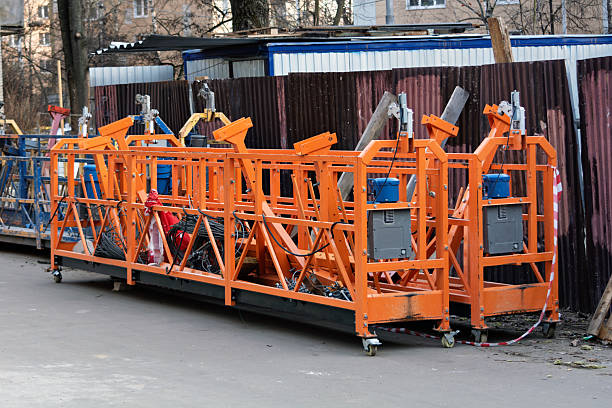 Multiple suspended scaffold platforms stand on site, showcasing industrial construction equipment used for facade work and repairs.